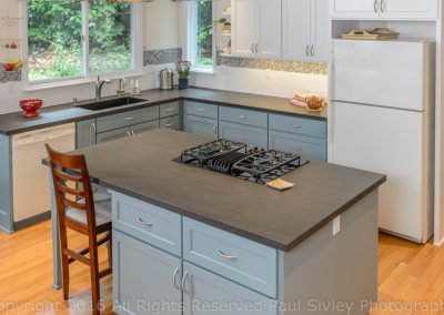 Dekton countertops kitchen island, stove top, stool, and sink